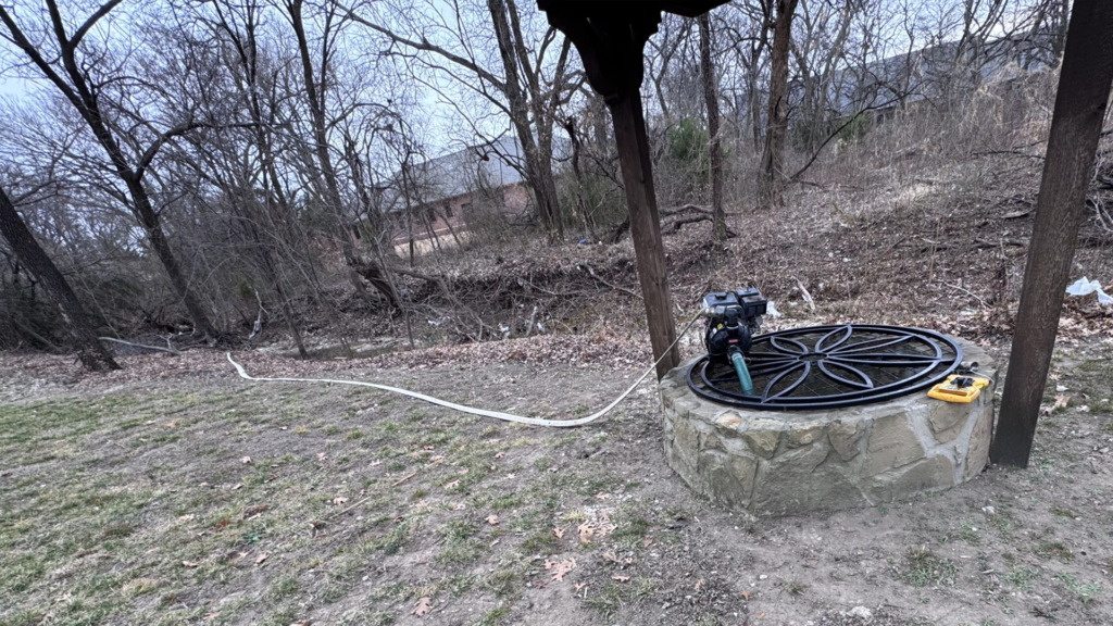 Portable pump and hose connected at covered outdoor well site