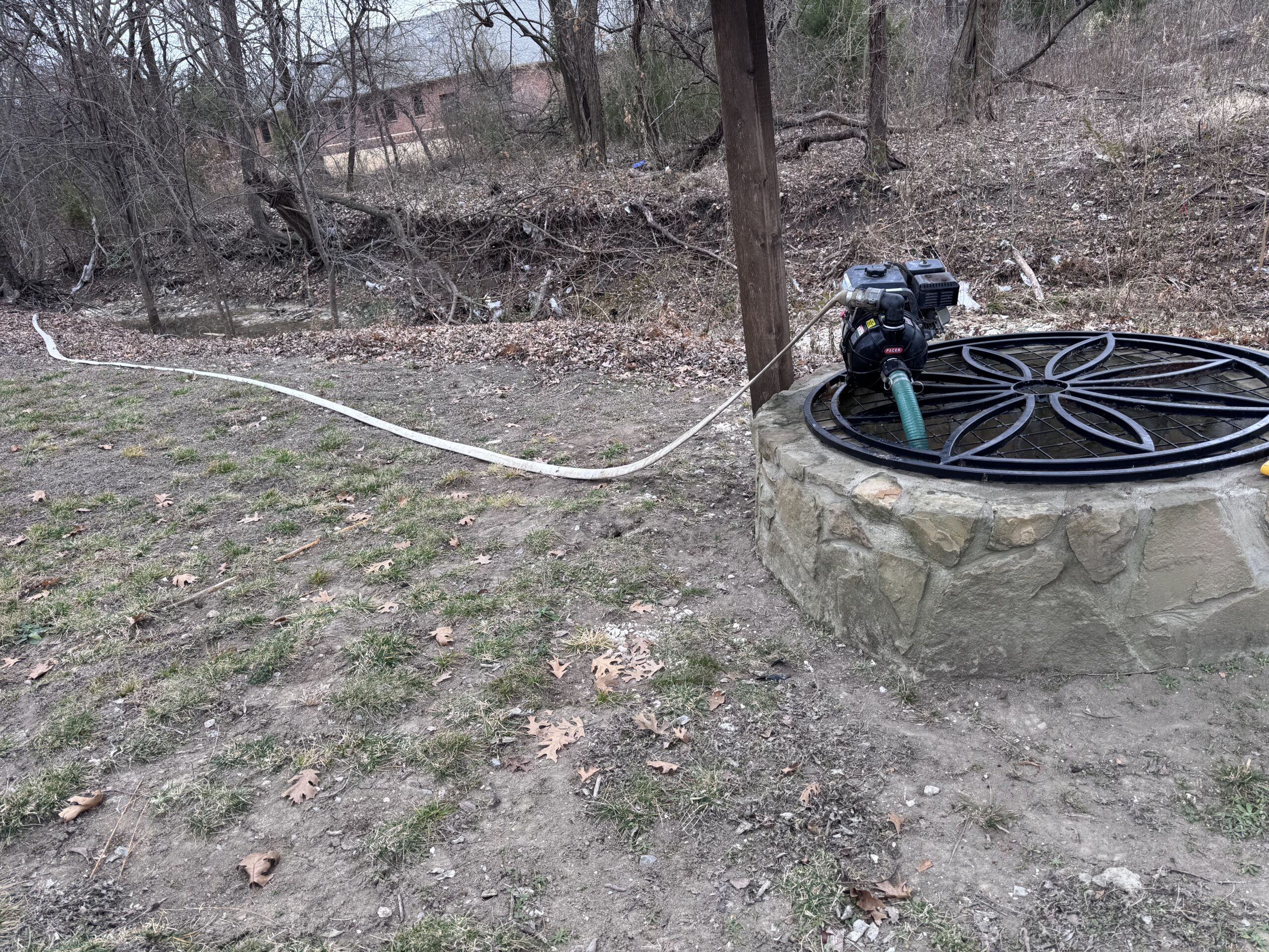 Portable pump and hose connected at covered outdoor well site