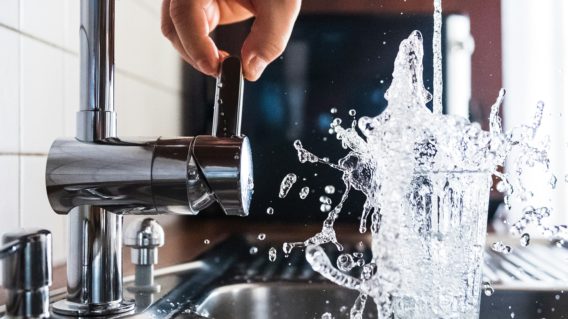 Glass being filled with clean water from modern kitchen faucet